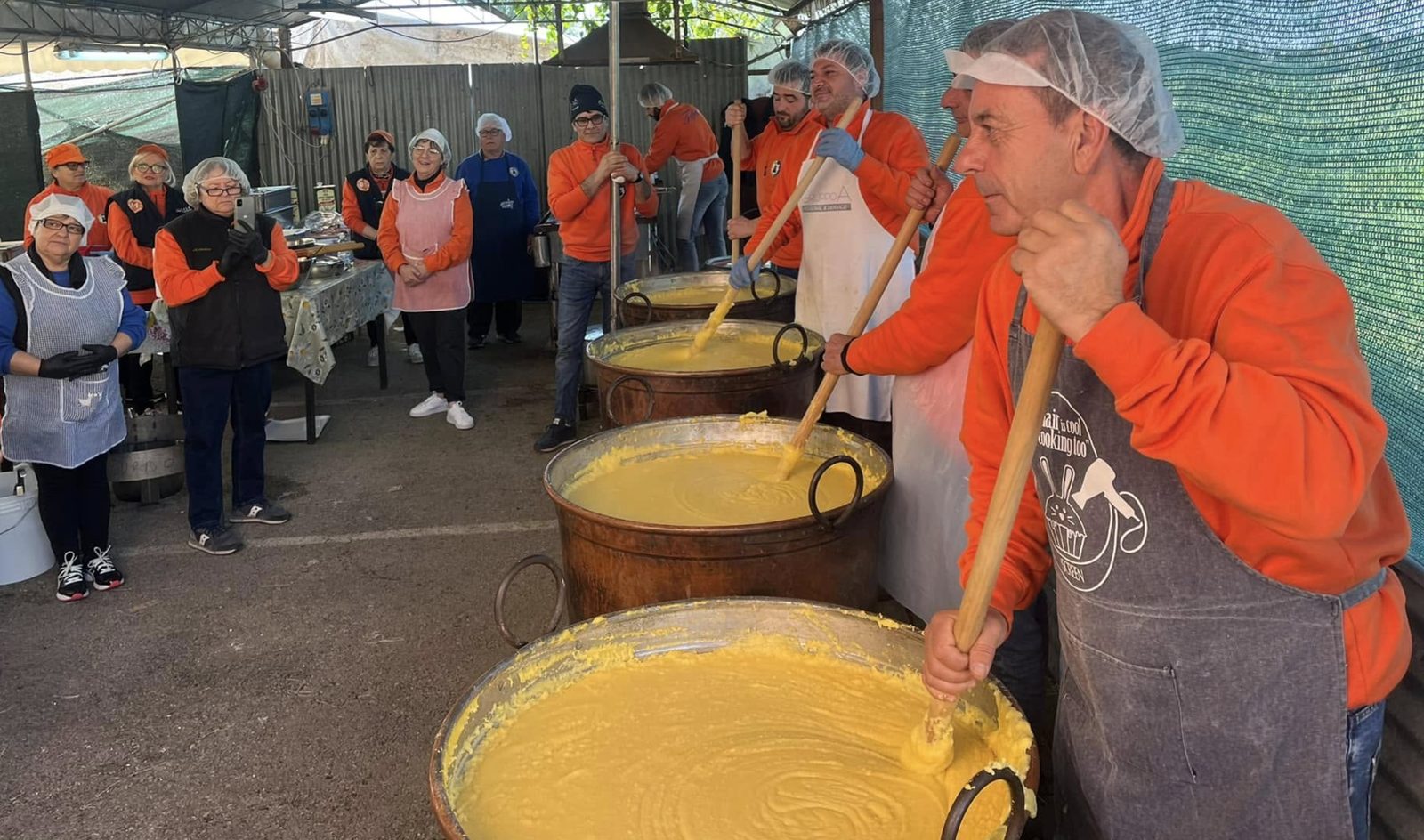 Volontari del Comitato mescolano la polenta nei grandi paioli di rame durante la sagra